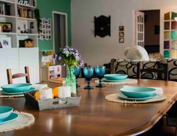 mesa comedor muy grande, con platos y copas turquesa decoración ehtnica, con sofa en el fondo