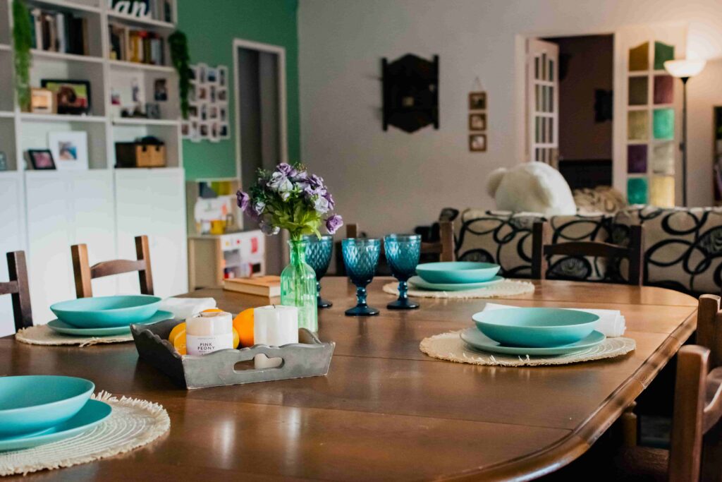 mesa comedor muy grande, con platos y copas turquesa decoración étnica, con sofá en el fondo